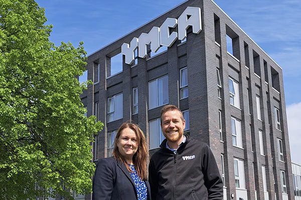 Director of Sales & Marketing for Black Country Chamber of Commerce and YMCA Black Country CEO, standing outside YMCA building, smiling to camera on a sunny day.