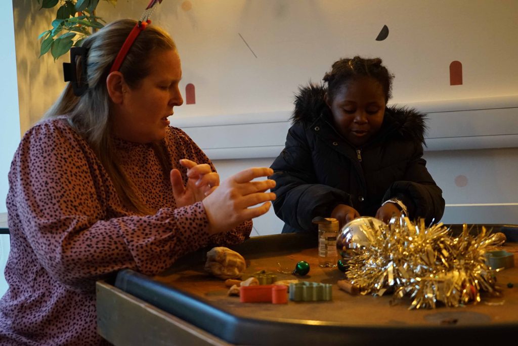 Nursery practitioner with a child playing with scented play dough at Christmas