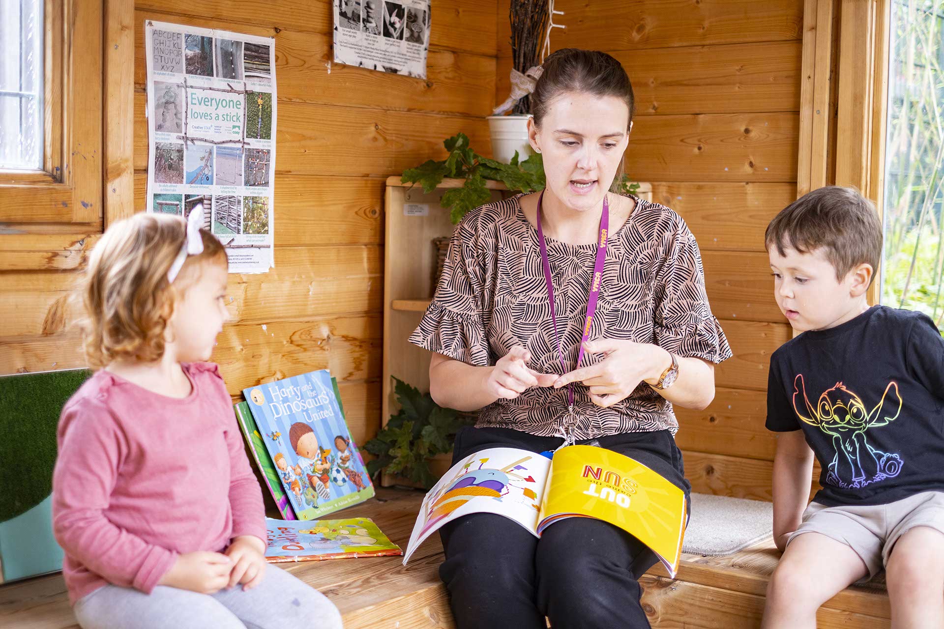 Nursery worker reading book to children in YMCA day nursery