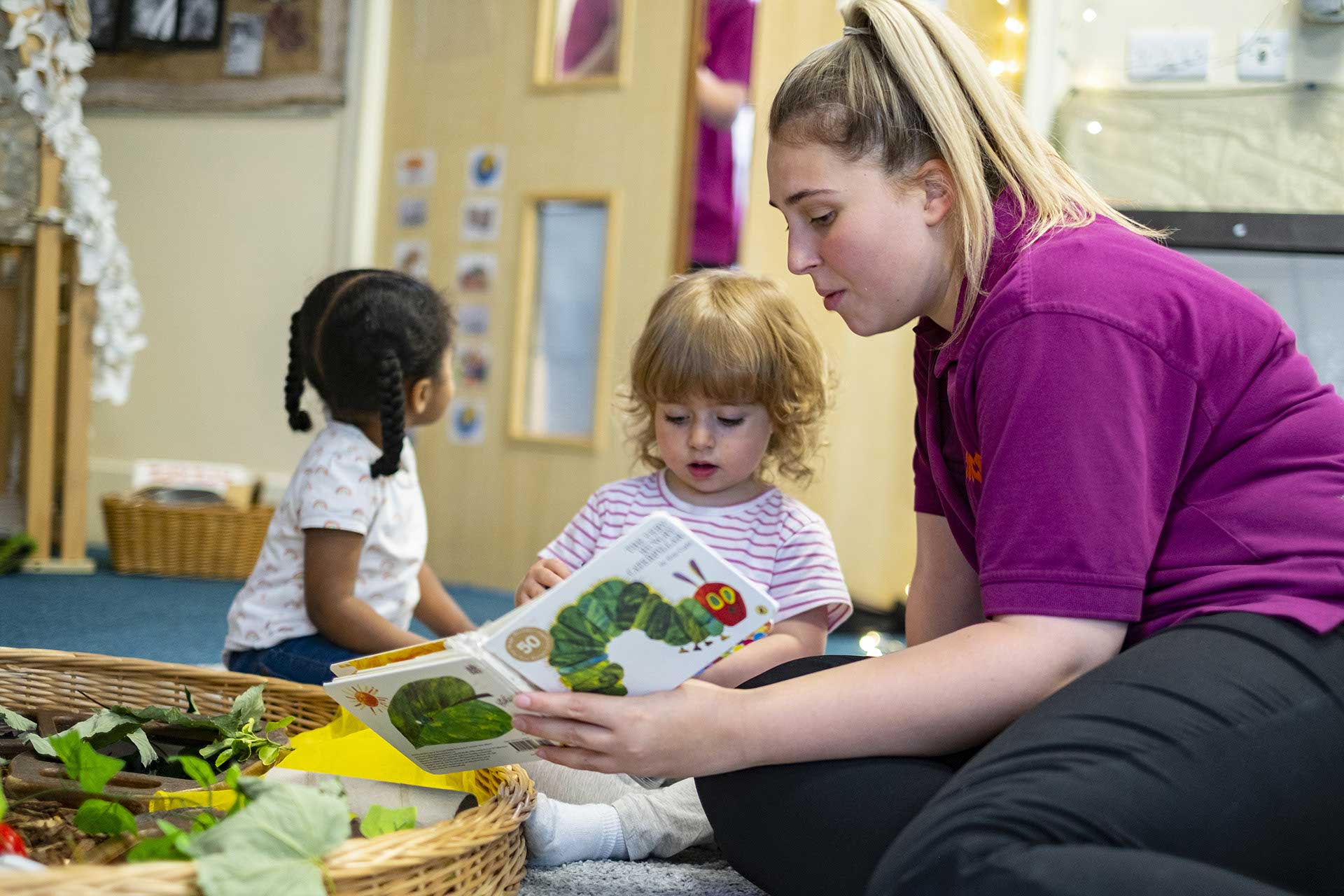 Nursery worker reading a book with a little girl at YMCA Day Nursery