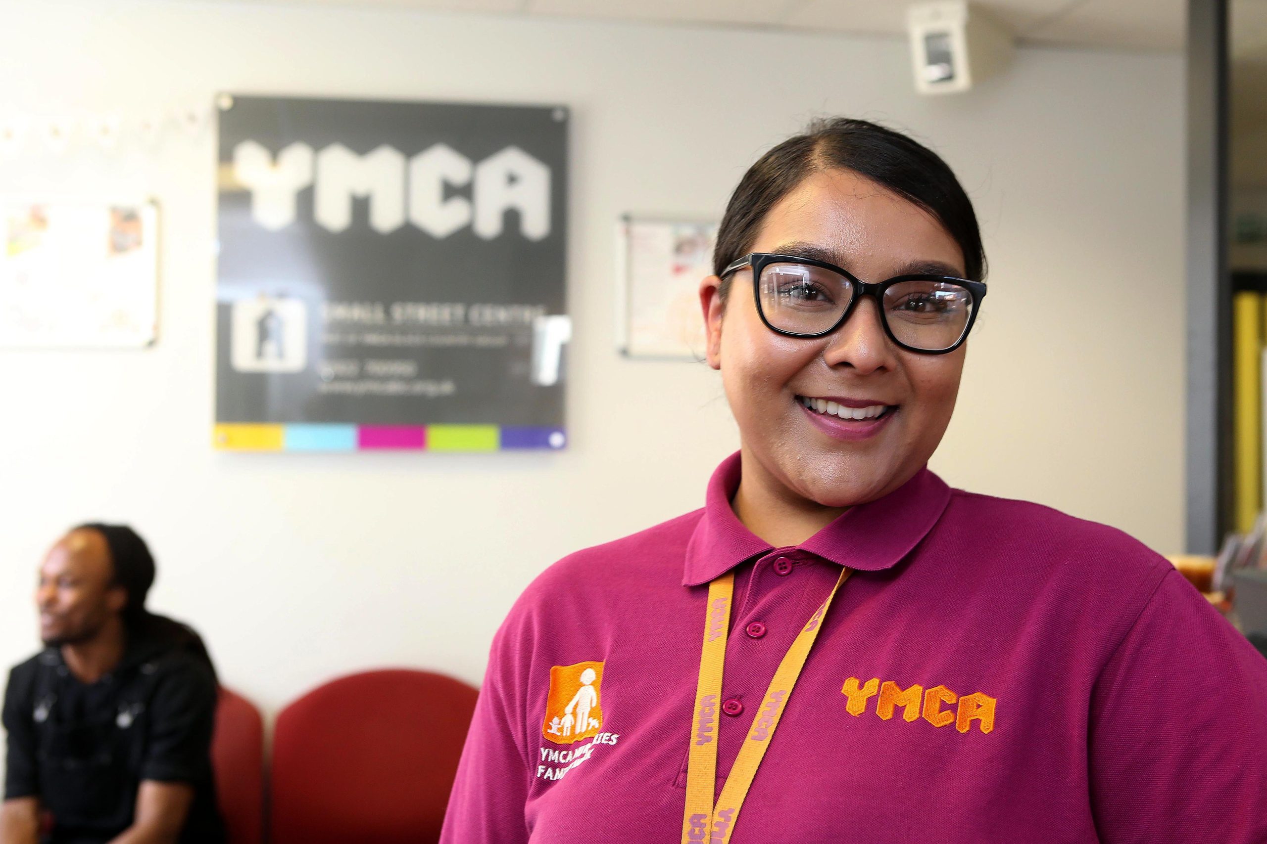 Smiling YMCA nursery staff member welcoming parents to reception