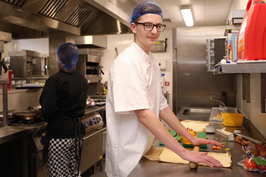 young man learning to cook in ymca kitchen