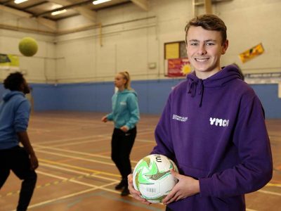 young man holding a football at ymca sports hall