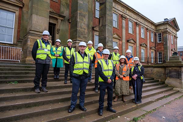 A group of professional in high vis and PPE standing on the front steps of the Wolverhampton Royal Quarter redevelopment, smiling to camera.
