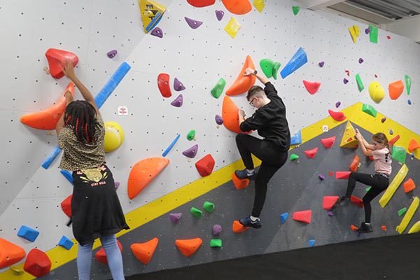 Children trying out new routes at a climbing wall participating in YMCA youth club